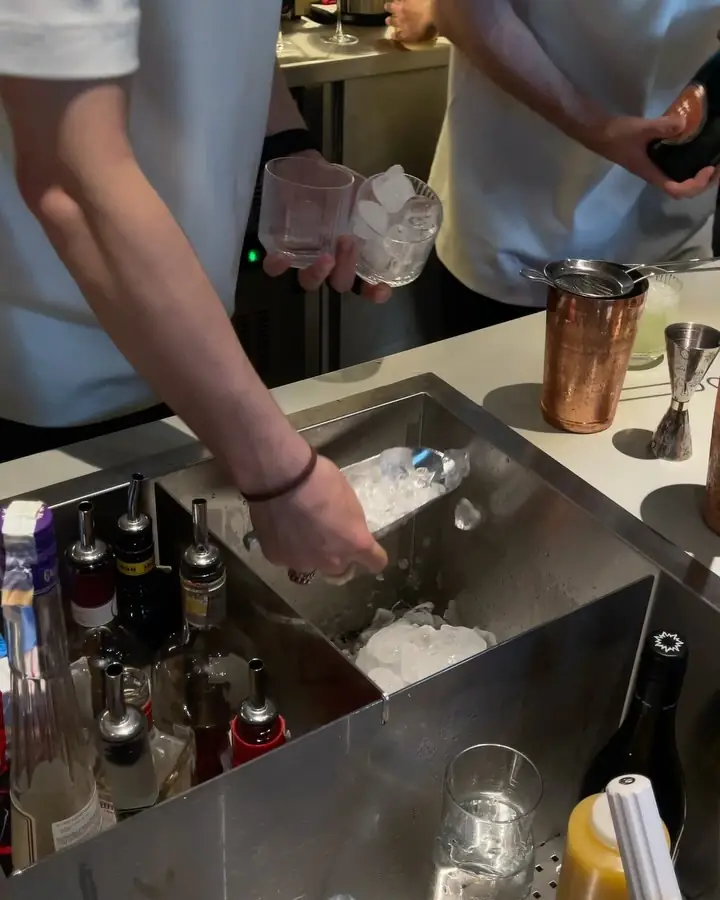 Bartenders building drinks over a well of ice