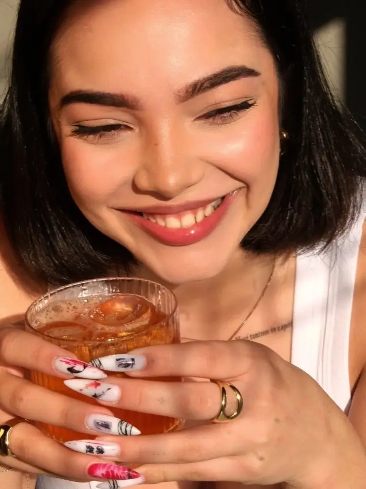 A guest smiling over an iced cocktail in golden light